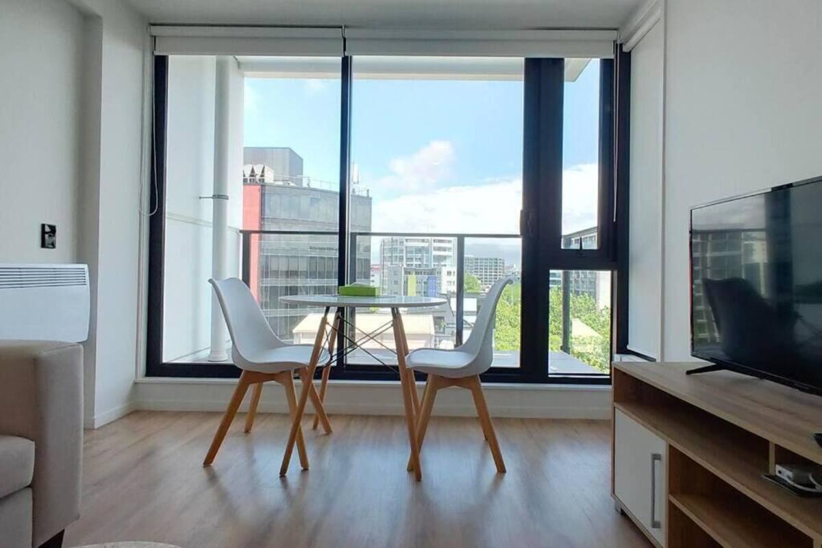 Una sala de estar moderna con un ventanal grande, un televisor de pantalla plana, una mesa de comedor con sillas y un sofá.