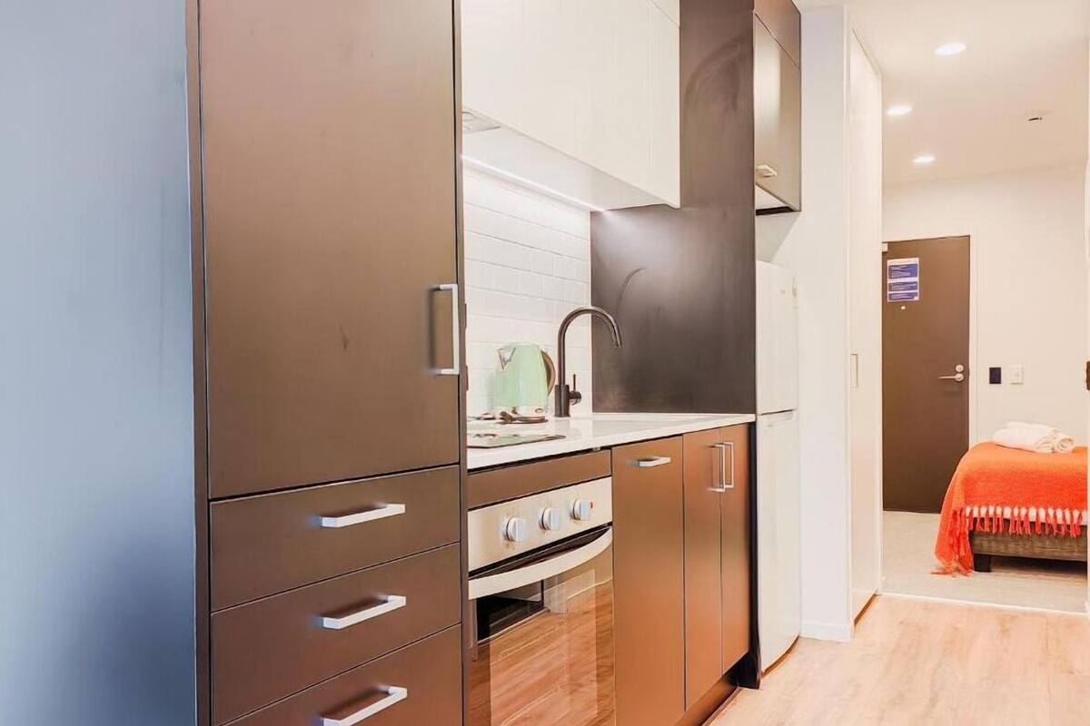 Una cocina moderna con armarios marrones, encimera blanca y campana de acero inoxidable.