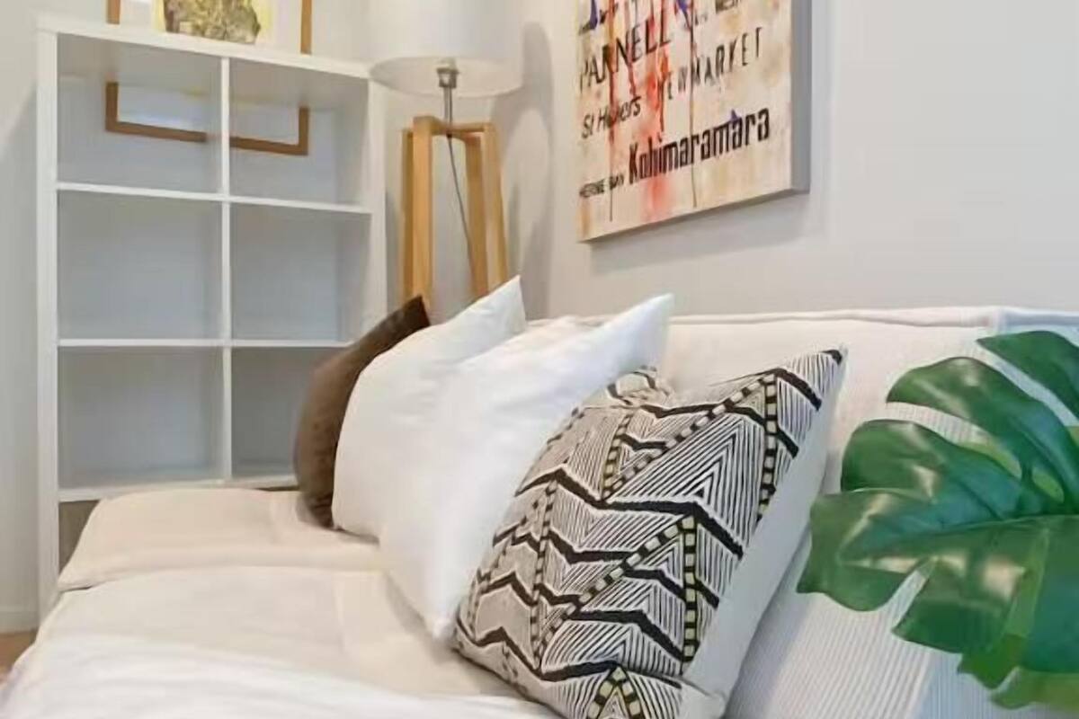 Un dormitorio moderno con una cama, una estantería blanca, una lámpara de pie y un cuadro abstracto grande en la pared.