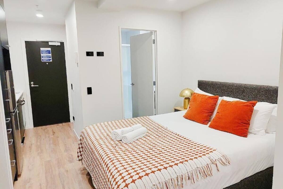 Una habitación de hotel con una cama, una mesita de noche con una lámpara y una puerta.