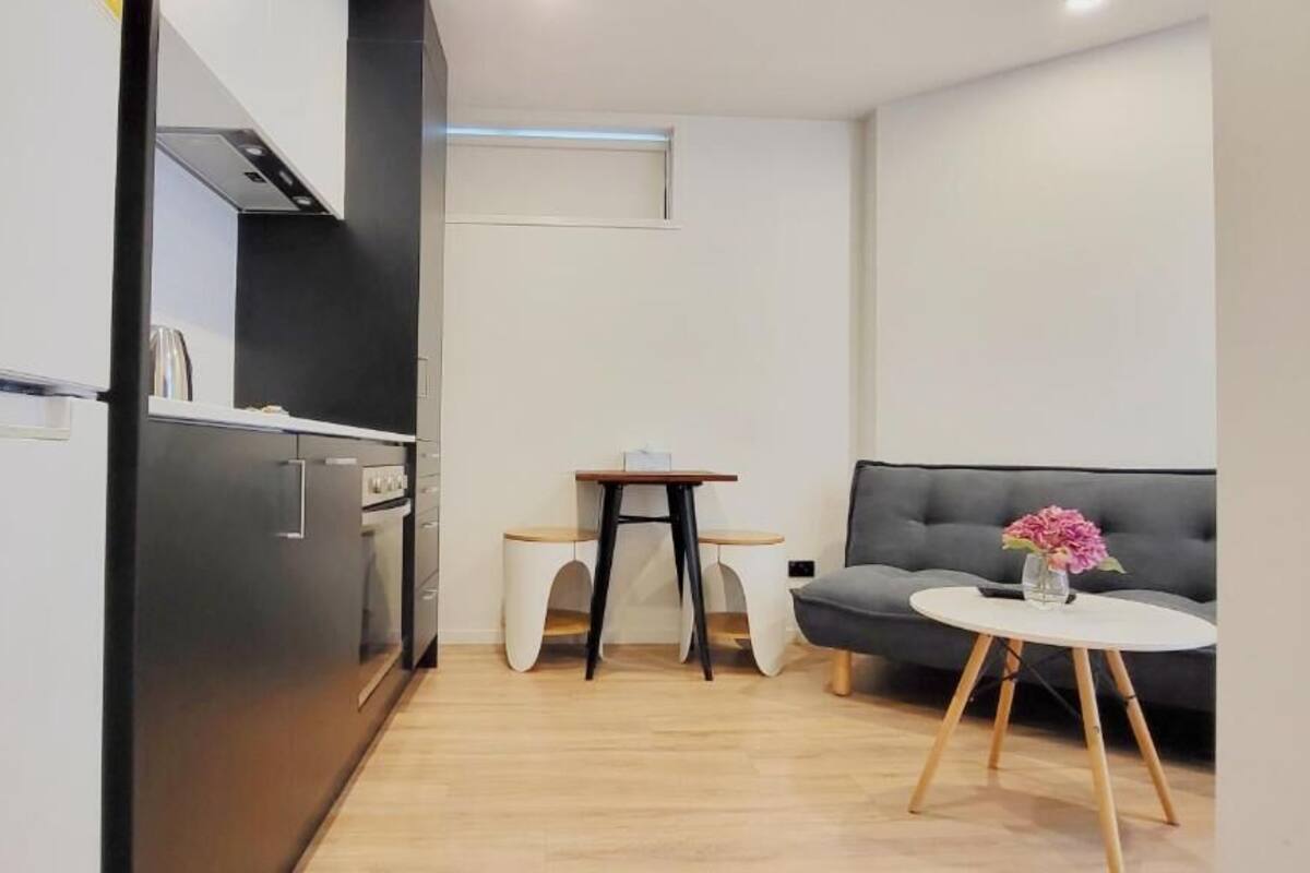 Un espacio habitable compacto con kitchenette, un sofá y una pequeña mesa.