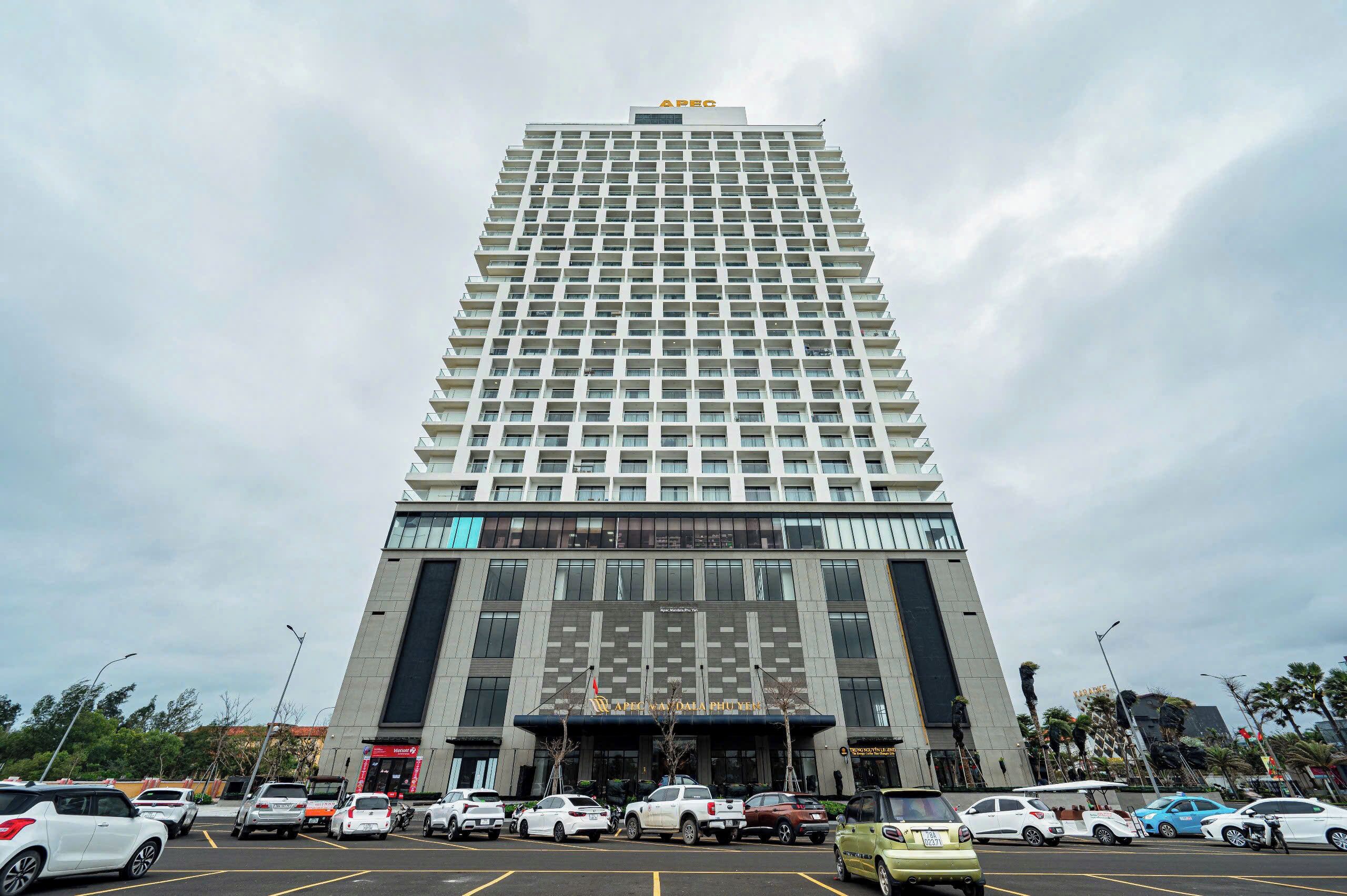A tall hotel with a modern design, featuring a prominent APEC logo at the top.