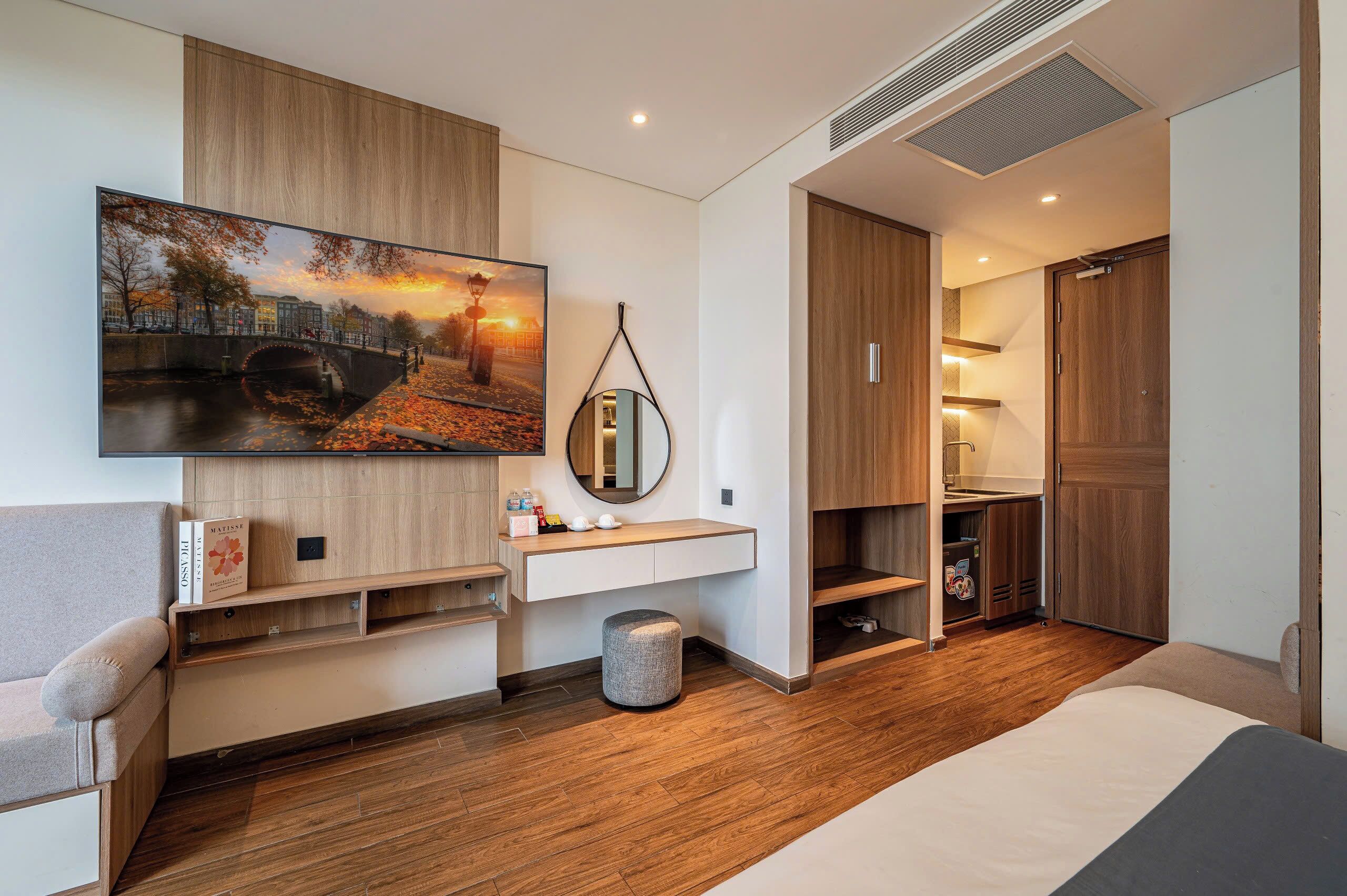 Ein modernes Schlafzimmer mit einem großen Bett, einem fest eingebauten Schreibtisch, einem an der Wand befestigten Fernseher und einem Kleiderschrank.