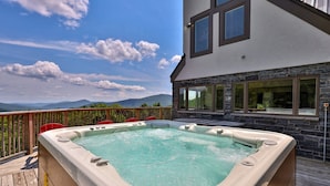 A hot tub on a wooden deck with a mountain view.