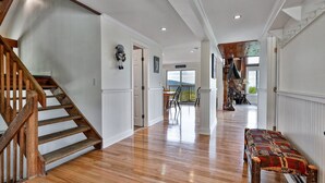A spacious hallway with wooden flooring, a wooden staircase, and a bench.
