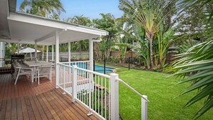 Un patio cubierto con una piscina, rodeado de exuberante follaje y palmeras.