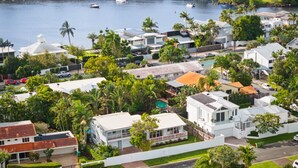Zona residencial costera con casas, una carretera y una masa de agua con barcos.