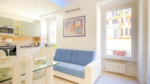 Un apartamento moderno con cocina, comedor y sala de estar con sofá y un ventanal grande.
