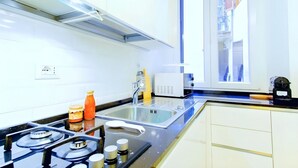 A modern kitchen with a gas stove, stainless steel sink, and a window overlooking a residential area. - Elegantis.it Milos Suite Apartment - Your Chic Retreat in Central Rome (Roma)