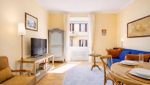 A living room with a television, sofa, and dining area. - Elegantis.it Milos Suite Apartment - Your Chic Retreat in Central Rome (Roma)