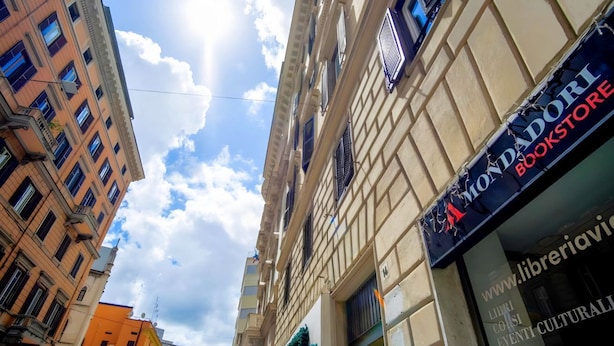 A street view with a bookstore named 'MondoDori Bookstore' and a building with a sign that reads 'www.libreriavi'. - Elegantis.it Milos Suite Apartment - Your Chic Retreat in Central Rome (Roma)