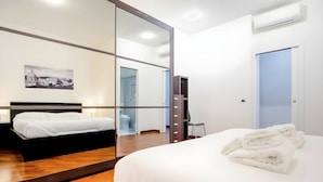 A hotel room with a bed, a mirror, a wardrobe, a toilet, and a picture on the wall.