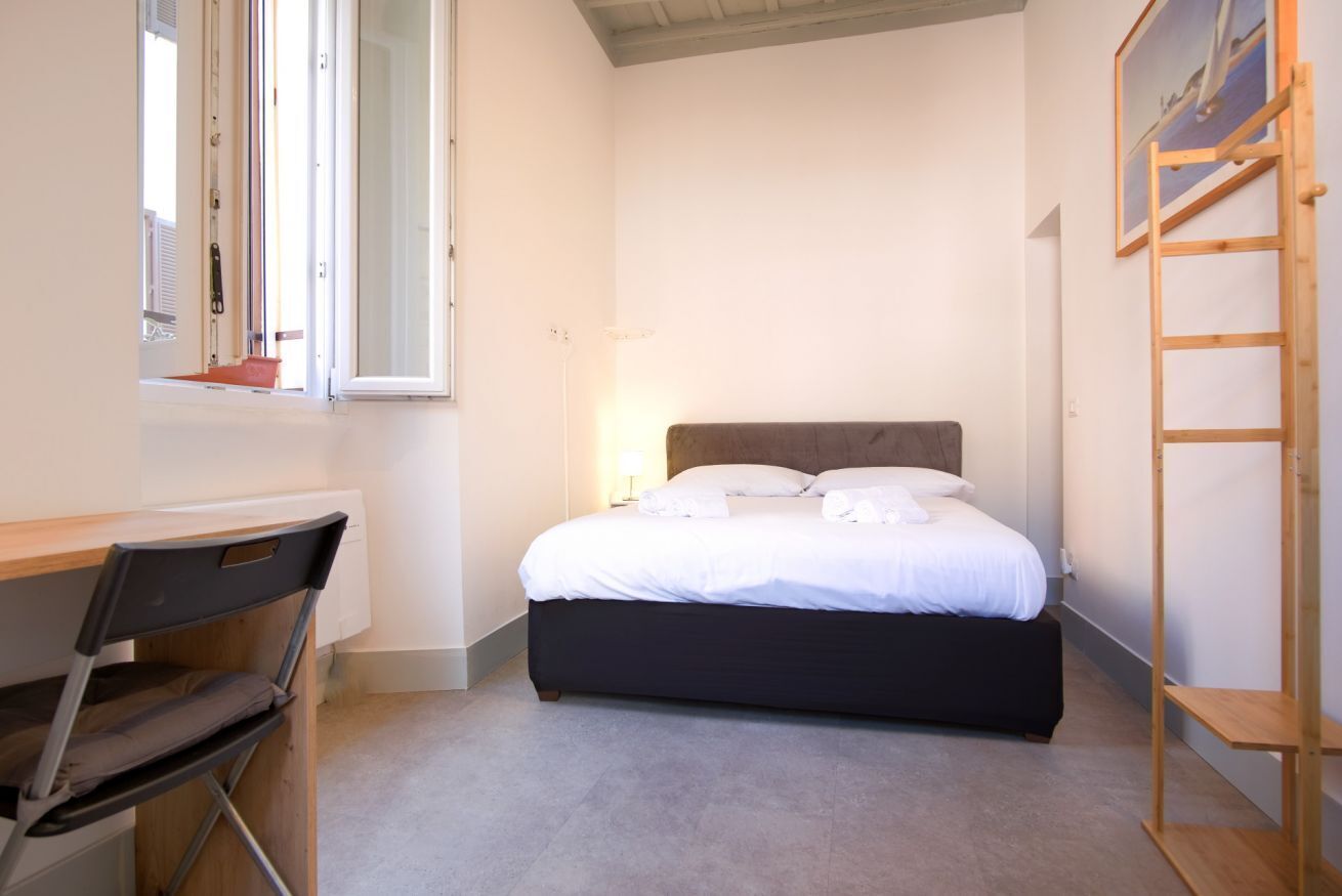 Une chambre à coucher avec un lit, un bureau, une chaise et une échelle.