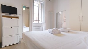 A hotel room with a bed, a TV, a dresser, a radiator, and a window. - Elegantis.it Trastevere Modern Apartment Comfort in Rome Most Charming District (Roma)