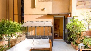 A cozy outdoor seating area with a cushioned bench, a canopy, and potted plants.