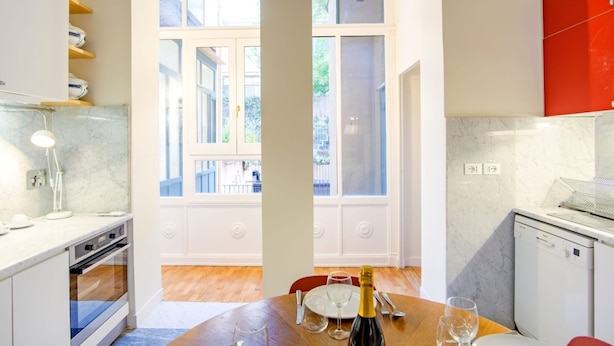 A modern kitchen with a dining area, large windows, and a view of the outside.