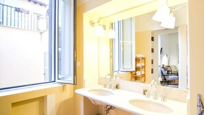 A bathroom with two sinks, a large mirror, and a window.