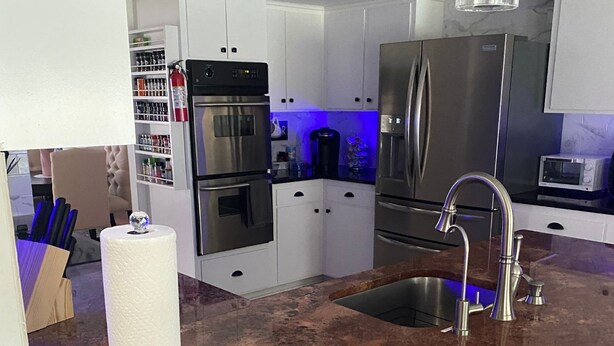 Cocina moderna con electrodomésticos de acero inoxidable, encimera de granito y dispensador de agua a la vista.