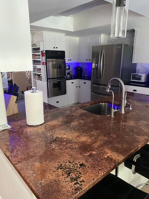 Cocina moderna con electrodomésticos de acero inoxidable, encimera de granito y dispensador de agua a la vista.