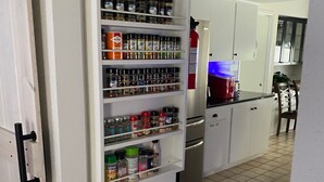Una cocina con especiero empotrado, refrigerador y zona de comedor con sillas.