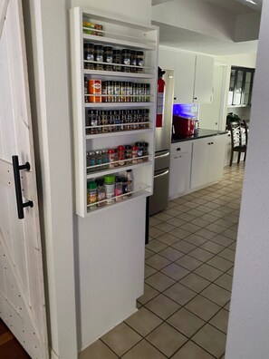 Eine Küche mit integriertem Gewürzregal, einem Kühlschrank und einem Essbereich mit Stühlen.