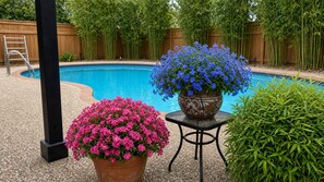 Un área de piscina con valla de madera, escalera y plantas en macetas con flores.