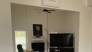 Una sala de estar con chimenea, televisor y ventilador de techo.
