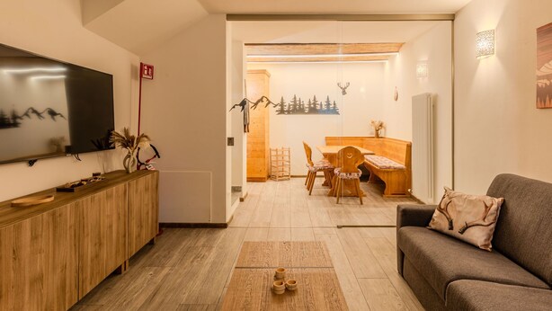Un salon moderne doté d’un téléviseur à écran plat, de meubles en bois et d’un coin salon confortable.