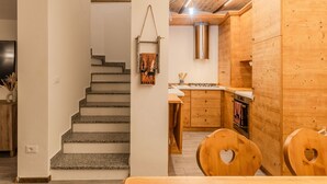 Une cuisine moderne avec des meubles en bois, une hotte de cuisine en acier inoxydable et une chaise en bois en forme de cœur.