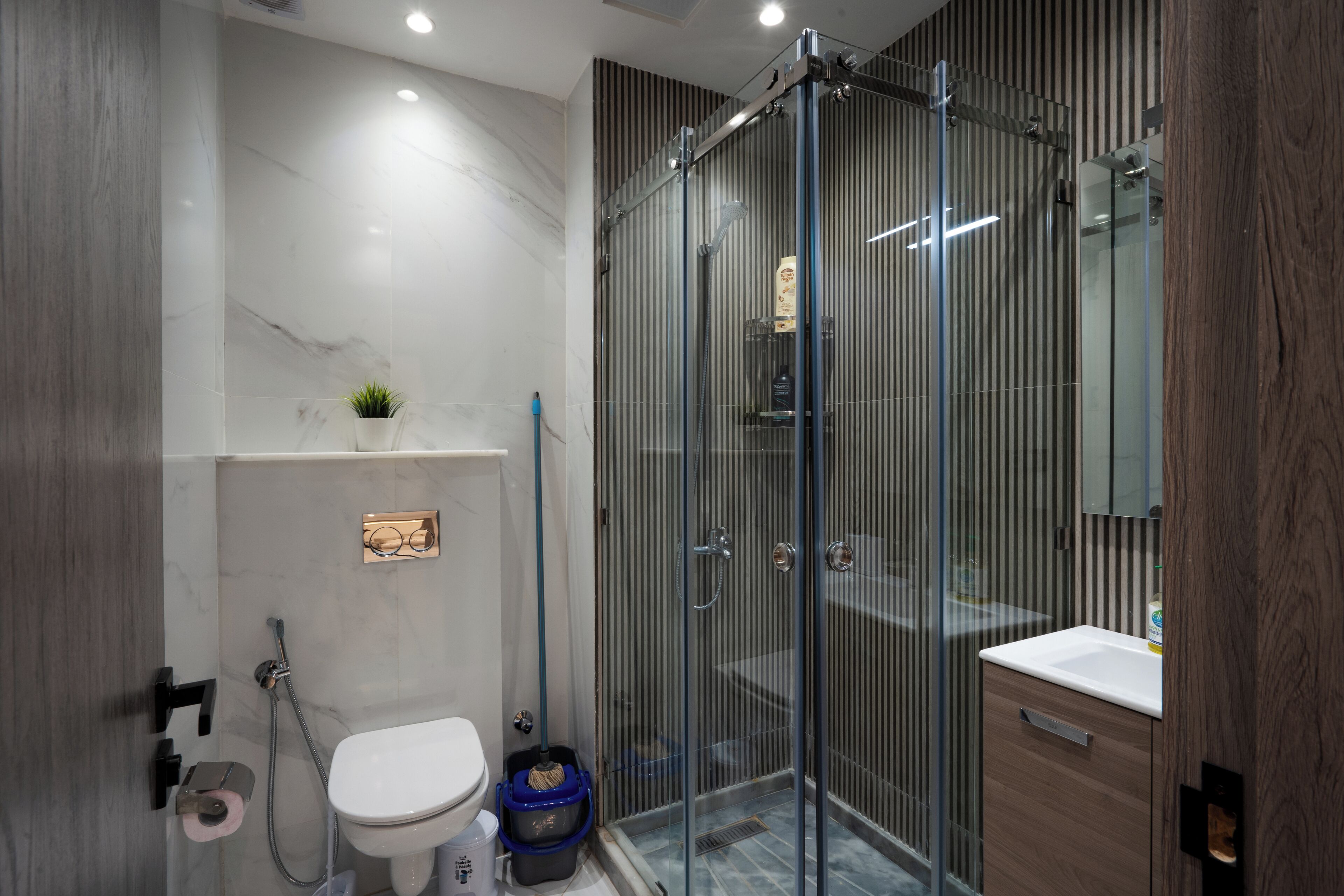 Un baño moderno con cabina de ducha de vidrio, inodoro y lavamanos.