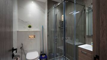 Un baño moderno con cabina de ducha de vidrio, inodoro y lavamanos.