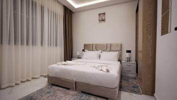 Een moderne slaapkamer met een groot bed, nachtkastjes, een garderobe en een plafondlamp.