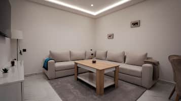 A modern living room with a beige sofa, a wooden coffee table, and a grey rug.