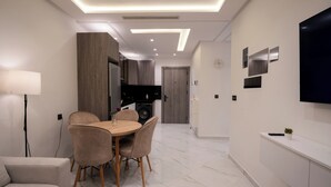 A modern kitchen with a dining area, a sofa, and a TV mounted on the wall. - Living Appart Hotel (Tangier)