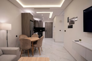 Una cocina moderna con comedor, sofá y televisor en la pared.