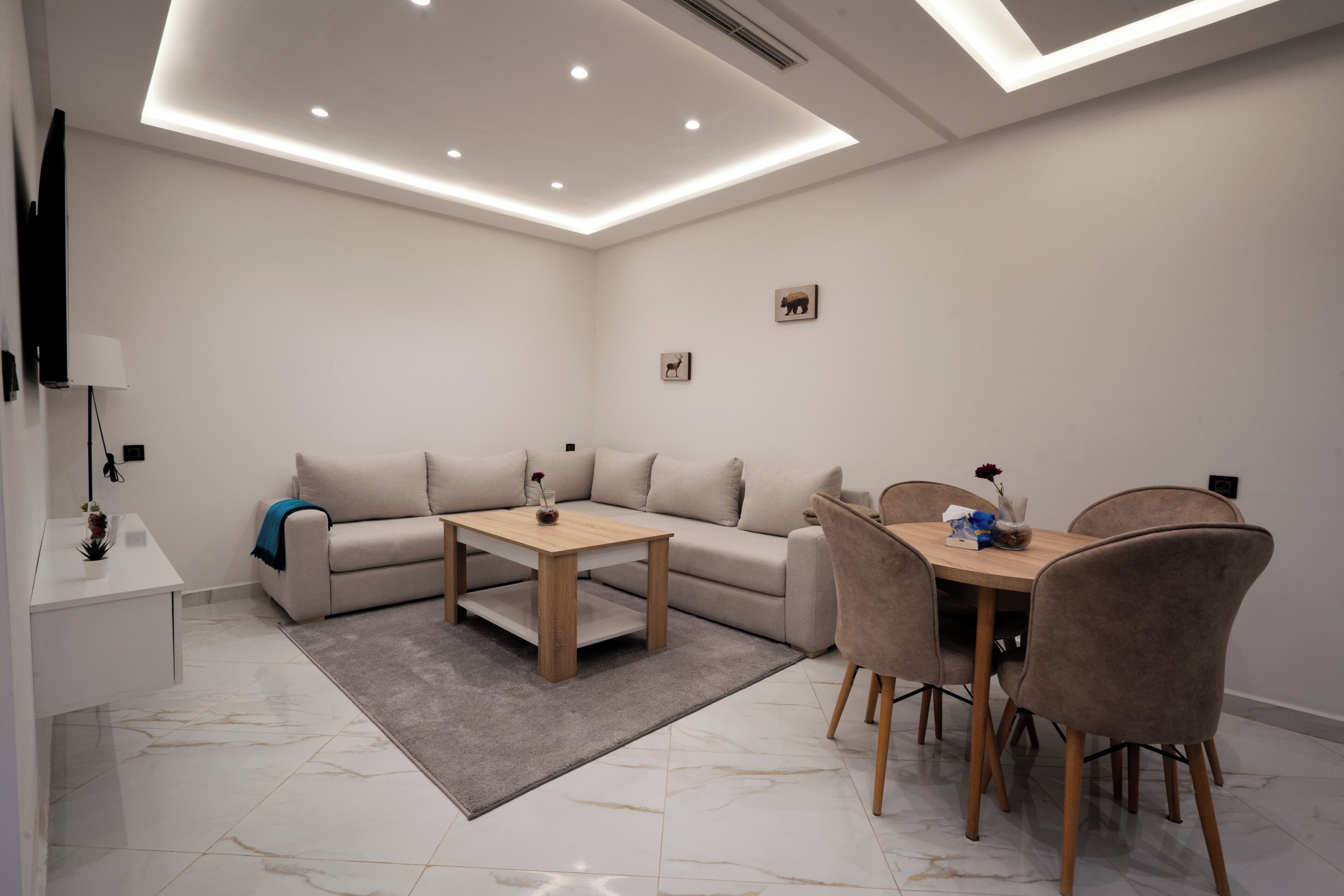 A modern living room with a sofa, a wooden coffee table, and a dining table with chairs.