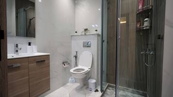 Un baño moderno con inodoro, lavabo y zona de ducha.