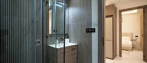 A modern bathroom with a glass shower enclosure, a wooden vanity, and a large mirror.