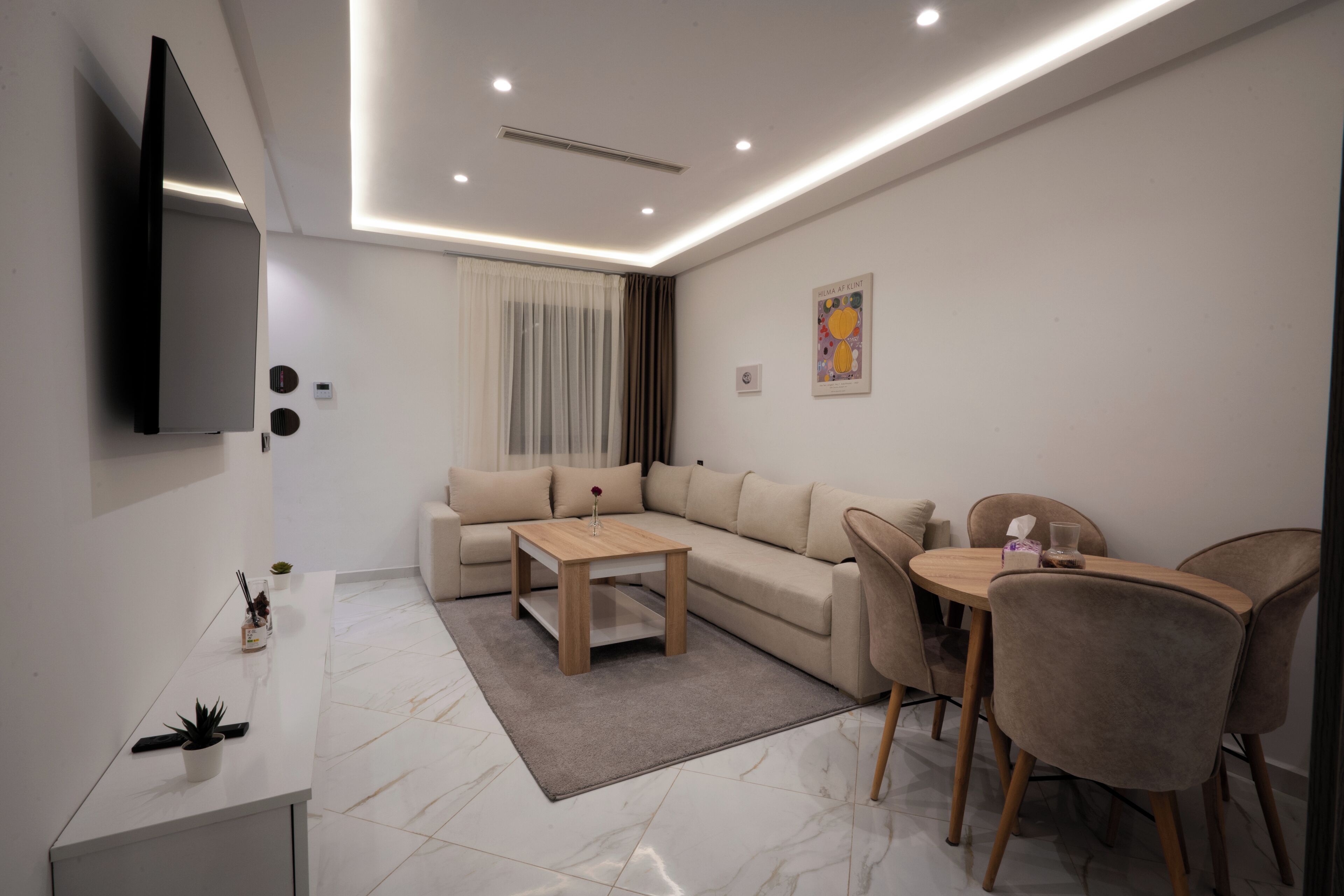 A modern living room with a sectional sofa, a coffee table, and a dining area with chairs.