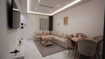 Un salon moderne avec un canapé d’angle, une table basse et un coin repas avec des chaises.