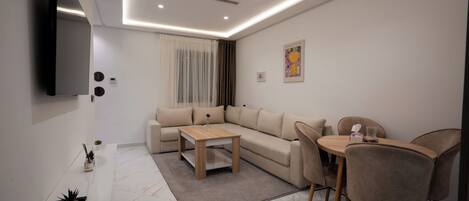 A modern living room with a sectional sofa, a coffee table, and a dining area with chairs.