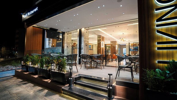 A modern café restaurant with outdoor seating and a well-lit entrance. - Living Appart Hotel (Tangier)