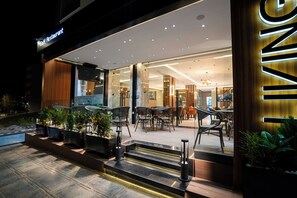 A modern café restaurant with outdoor seating and a well-lit entrance. - Living Appart Hotel (Tangier)
