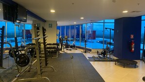A gym with various exercise equipment, large windows, and a fire extinguisher on the wall. - Oceanfront in Coronado Bay (Las Lajas)