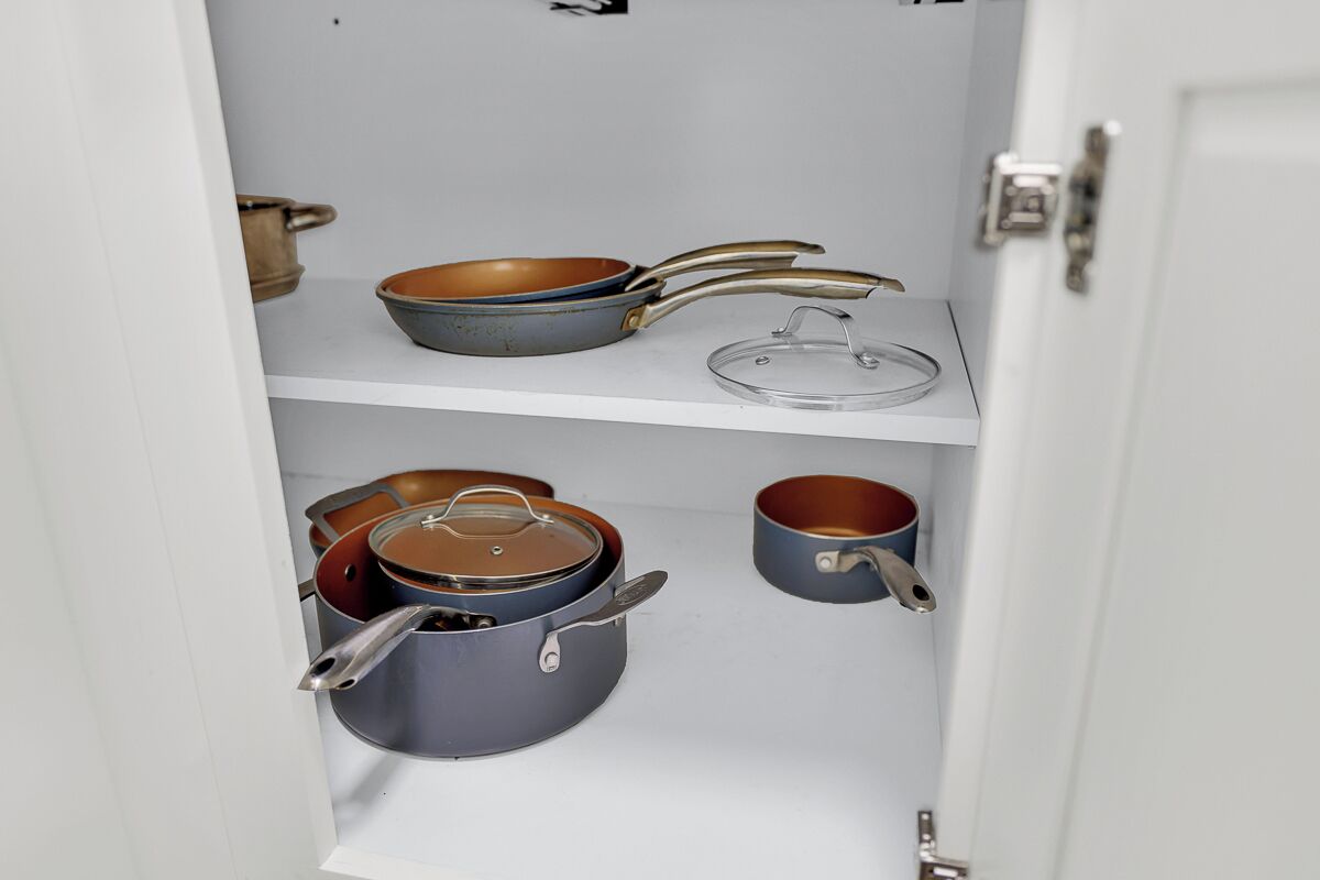 A kitchen cabinet with various pots and pans.