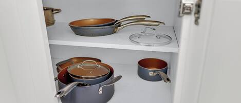 A kitchen cabinet with various pots and pans.