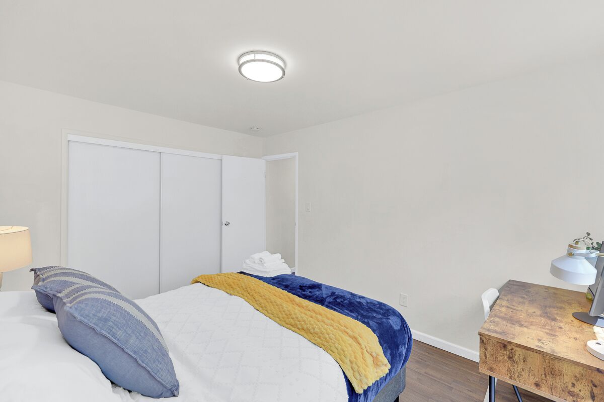 A bedroom with a bed, a desk, and a wardrobe.