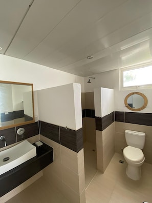A bathroom with a white sink, a toilet, and a shower area.