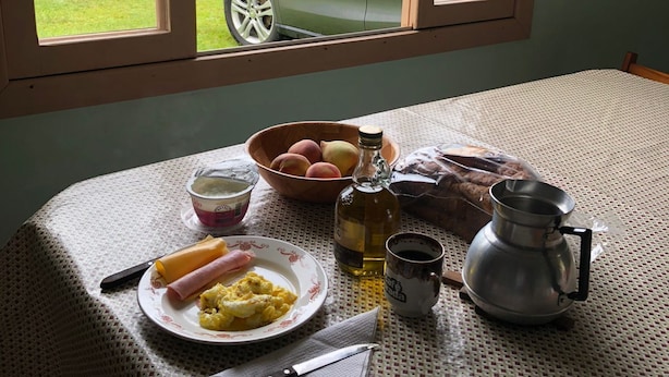 Ein Esstisch mit Frühstücksgebäck und Blick auf ein grünes Auto durch ein Fenster.