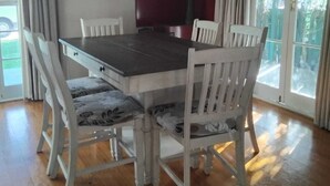 A dining area with a rectangular table surrounded by six white chairs with floral upholstery. - Charming 3-bedroom house walking distance to the wonderful Napier, marine parade (Napier)